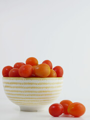 Cherry tomatoes in a ceramic bowl and white background.