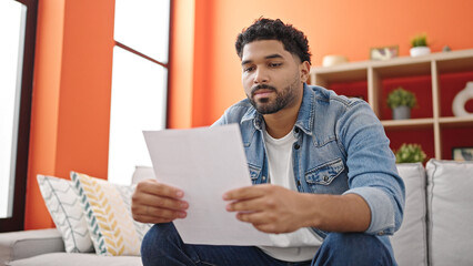 African american man reading document sitting on sofa at home