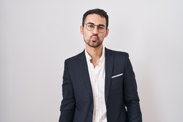 Handsome business hispanic man standing over white background looking at the camera blowing a kiss...