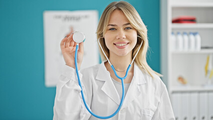 Young blonde woman doctor smiling confident holding stethoscope at clinic