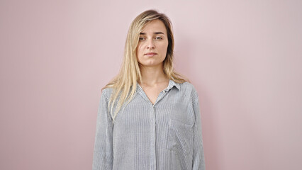 Obraz premium Young blonde woman standing with serious expression over isolated pink background