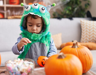 Adorable hispanic boy having halloween party holding sweets at home