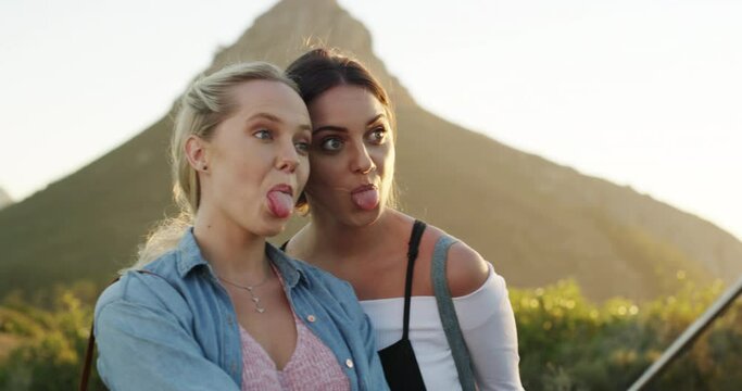 Girl friends, tongue out and selfie stick on nature hike with phone and travel in mountains. Young people, women and mobile picture for social media app and network on vacation with funny face