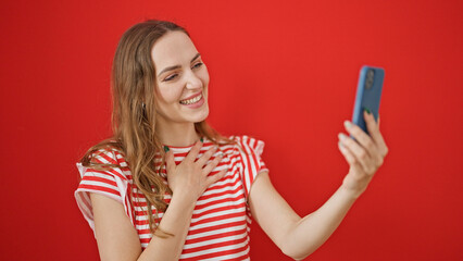 Young blonde woman smiling confident having video call over isolated red background