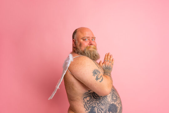 Fat man with beard ,tattoos and wings acts like an angel