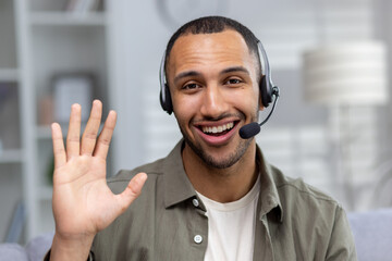 Close-up photo. Face portrait of a smiling young African American man at home wearing a headset...