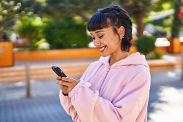 Young woman smiling confident using smartphone at park