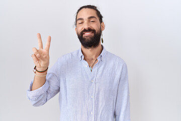 Naklejka premium Hispanic man with beard wearing casual shirt showing and pointing up with fingers number two while smiling confident and happy.