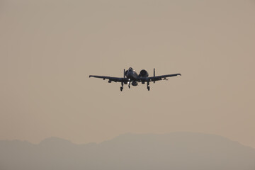 Fototapeta na wymiar Fighter jet in silhouette over an evening sky with a mountain backgroud