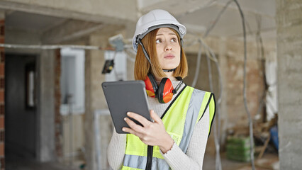 Young blonde woman architect using touchpad with serious expression at construction site