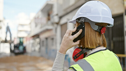 Young blonde woman architect talking on smartphone at street