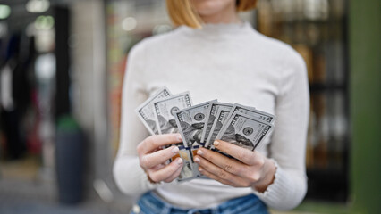 Young blonde woman counting dollars at street