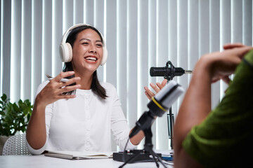 Young woman laughing when talking to guest of her podcast - obrazy, fototapety, plakaty