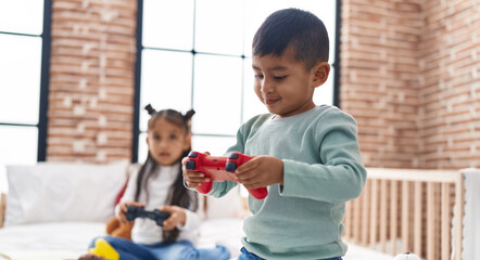 Adorable boy and girl playing video game sitting on sofa at bedroom