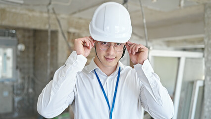 Young hispanic man architect smiling confident wearing glasses at construction site