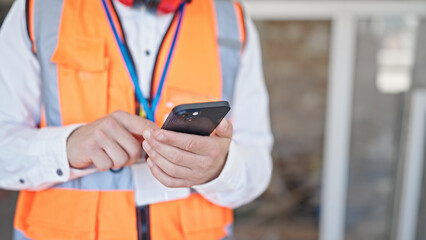 Young caucasian man architect using smartphone at construction site
