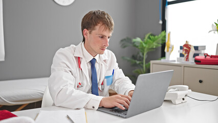 Young caucasian man doctor using laptop working at clinic