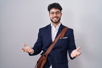 Hispanic man with beard wearing business clothes smiling cheerful with open arms as friendly welcome, positive and confident greetings - obrazy, fototapety, plakaty