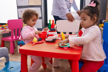 Adorable girls playing supermarket game sitting on table at kindergarten
