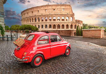 Little red old Fiat 500 in front of coliseum at sunset with picnic basket on rear - obrazy, fototapety, plakaty