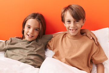 Adorable boys hugging each other sitting on sofa at bedroom