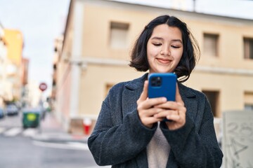 Young woman smiling confident using smartphone at street