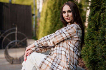 A girl in a plaid shirt sits on a bench. Portrait of a beautiful girl