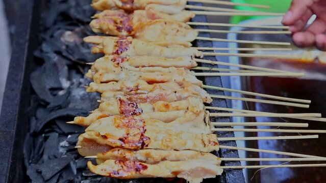 Side view of roasting chicken satay, bokeh video image