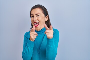 Middle age hispanic woman standing over isolated background pointing fingers to camera with happy and funny face. good energy and vibes.