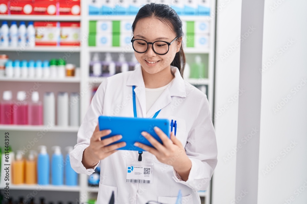 Sticker young chinese woman pharmacist using touchpad working at pharmacy