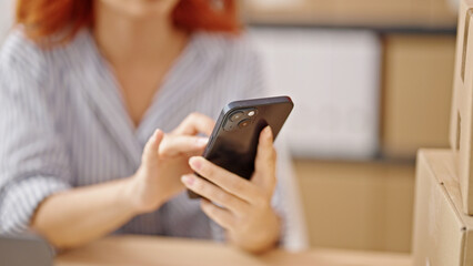 Young redhead woman ecommerce business worker using smartphone at office