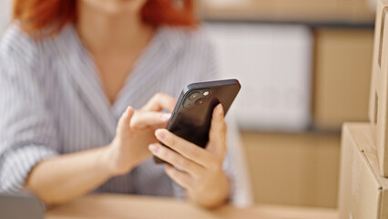 Fototapeta na wymiar Young redhead woman ecommerce business worker using smartphone at office