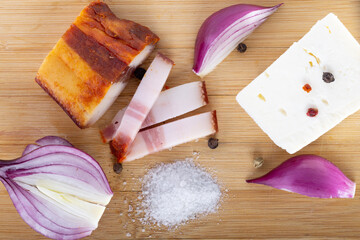Romanian smoked bacon with cheese, onions, salt and pepper on a wood board, traditional rustic heatlhy food 