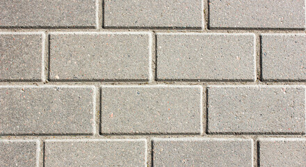 Brick paving slabs.Gray background of a brick pavement.Background of a block of gray stone tiles Surface of a gray brick.Stone pavement slab texture. Road,tile,concrete slab.