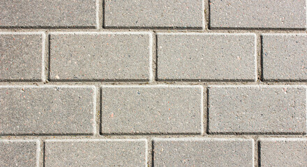 Obraz premium Brick paving slabs.Gray background of a brick pavement.Background of a block of gray stone tiles Surface of a gray brick.Stone pavement slab texture. Road,tile,concrete slab.