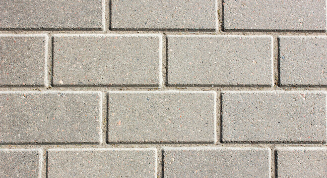 Fototapeta Brick paving slabs.Gray background of a brick pavement.Background of a block of gray stone tiles Surface of a gray brick.Stone pavement slab texture. Road,tile,concrete slab.
