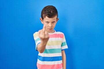 Young caucasian kid standing over blue background showing middle finger, impolite and rude fuck off...