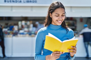 Young african american woman smiling confident reading book at street