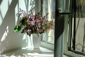 A bouquet of lilacs on the windowsill in the sun
