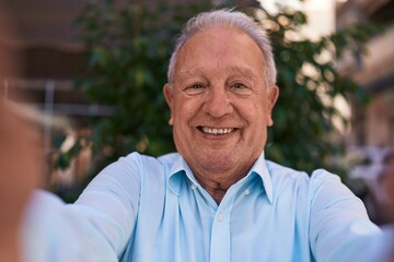 Middle age grey-haired man smiling confident making selfie by camera at street