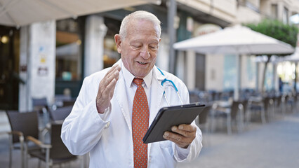 Senior grey-haired man doctor smiling confident having video call at coffee shop terrace