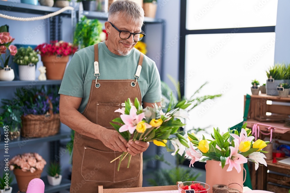 Wall mural Middle age grey-haired man florist holding bouquet of flowers at flower shop