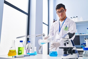 Down syndrome man wearing scientist uniform pouring liquid on test tube at laboratory