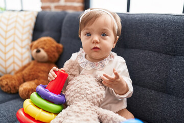 Adorable caucasian baby playing with hoops game sitting on sofa at home