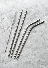 reusable stainless steel straws and cleaning brush in gray bag on gray background, eco friendly lifestyle