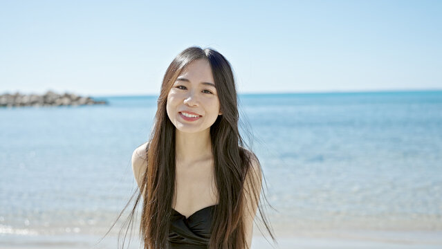 Young chinese woman tourist smiling confident wearing swimsuit at seaside