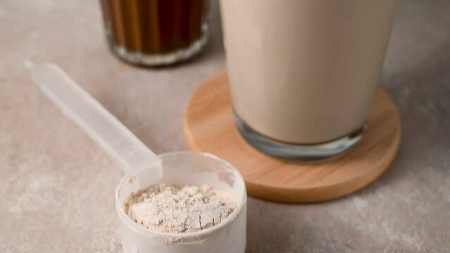 Protein powder in a scoop with two glasses of protein drink. Bodybuilding, fitness sport, health and nutrition.