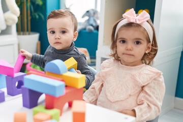 Fototapeta na wymiar Adorable boy and girl playing with construction blocks sitting on table at kindergarten