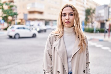 Fototapeta premium Young blonde woman standing with serious expression at street