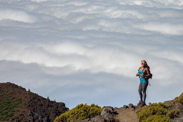 Female hiker at sunrise above the clouds at the beautiful Caldera de Taburiente National Park in La Palma - Canary Islands